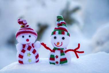 İki küçük komik oyuncak bebek kardan adam örgü şapkalı ve eşarplı açık havada açık havada açık mavi ve beyaz fotokopi arkaplanda. Mutlu yıllar ve Mutlu Noeller tebrik kartı.