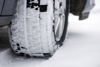 Ayrıntı araba tekerleği ile yeni siyah kauçuk lastik koruyucu kış karla kaplı yolda kapatın. Ulaşım ve güvenlik kavramı.