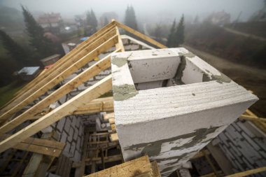 Çatı çerçeve kaba ahşap kereste kirişler ve plakalar üstten görünüm duvar içi boş köpük yalıtım bloklar kırsal manzara arka plan üzerinde yapılmış. Bina, çatı kaplama, inşaat ve yenileme kavramı.