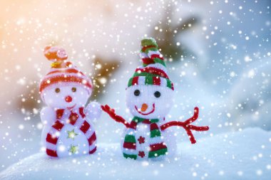 İki küçük komik oyuncak bebek kardan adam örgü şapkalı ve eşarplı açık havada açık havada açık mavi ve beyaz fotokopi arkaplanda. Mutlu yıllar ve Mutlu Noeller tebrik kartı.