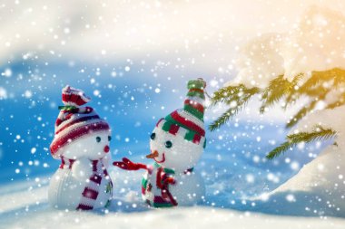 İki küçük komik oyuncak bebek kardan adam örgü şapkalı ve eşarplı açık havada açık havada açık mavi ve beyaz fotokopi arkaplanda. Mutlu yıllar ve Mutlu Noeller tebrik kartı.