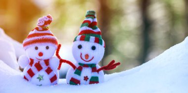 İki küçük komik oyuncak bebek kardan adam örgü şapkalı ve eşarplı açık havada açık havada açık mavi ve beyaz fotokopi arkaplanda. Mutlu yıllar ve Mutlu Noeller tebrik kartı.