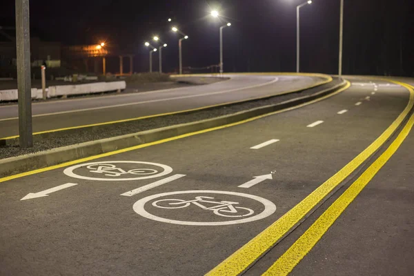 Bicycle Road Markings and Signs. Illuminated bicycle lane travel lane reserved for bicyclists with pavement markings with arrows that direct bicyclists in the direction of travel at night.