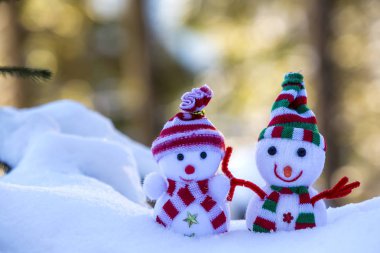 İki küçük komik oyuncak bebek kardan adam örgü şapkalı ve eşarplı açık havada açık havada açık mavi ve beyaz fotokopi arkaplanda. Mutlu yıllar ve Mutlu Noeller tebrik kartı.