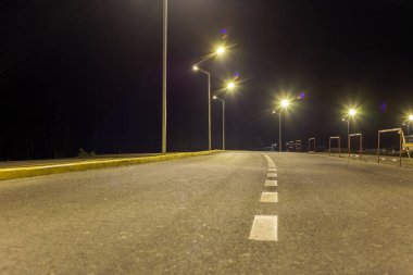 Geniş modern düz boş sokak lambaları asfalt karayolu ile parlak beyaz geceleri satırını imzala işaretleme ile aydınlatılmış. Hız, emniyet, rahat yolculuk ve profesyonel yol bina konsepti.