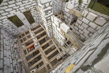 Yukarıdan gelecekteki multi depolanan yazlık enerji tasarrufu büyük beyaz içi boş köpük yalıtım blokları ve geçici ahşap iskele çerçeve görüntüleyin. İnşaat duvar, modern teknoloji kavramı.