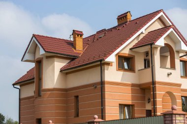 Büyük modern pahalı lüks konut iki-hikayeleri yazlık, Müstakil Ev shingled kahverengi bir çatı, yüksek tuğla bacalar, mavi gökyüzü kopya alan arka plan duvarlarda sıva. Gayrimenkul Satış konsepti.