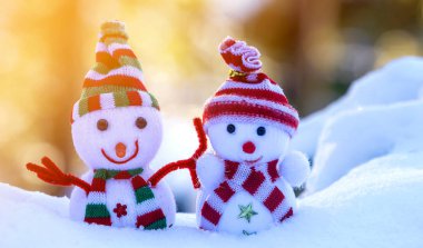 İki küçük komik oyuncak bebek kardan adam örgü şapkalı ve eşarplı açık havada açık havada açık mavi ve beyaz fotokopi arkaplanda. Mutlu yıllar ve Mutlu Noeller tebrik kartı.