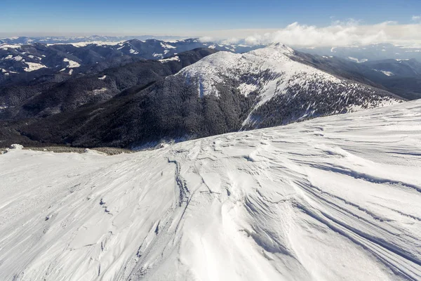 美丽的冬季风景 陡峭的高山山坡上 白雪纷飞 远山漫漫的山景绵延至地平线 蓝天闪烁着灿烂的太阳光复制着空间的背景 — 图库照片