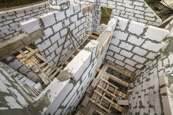 View from above of future multi stored cottage energy saving walls of large white hollow foam insulation blocks and temporary wooden scaffolding frame. Construction masonry, modern technology concept.