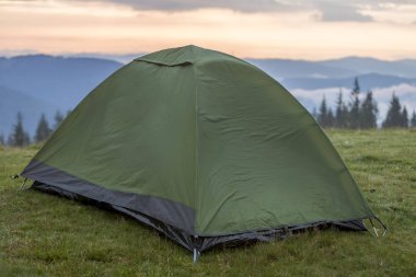 Çam ağacı başında, sisli dağlar ve daha önce gündoğumu kopya alan arka plan açık mavi pembe gökyüzü çimenli tepeye turist çadırın Close-up. Şafakta dağda kamp yaz. Turizm, hiking kavramı.