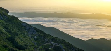 Dağ vadinin muhteşem manzarası kaplı düşük beyaz kabarık gibi kar sisli ufuk ışık turuncu parlamayı gündoğumu, parlak sabah gökyüzü altında uzanan bulutlar. Doğa kavramının güzellik.