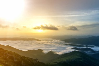 Dağ vadinin muhteşem manzarası kaplı düşük beyaz kabarık gibi kar sisli ufuk ışık turuncu parlamayı gündoğumu, parlak sabah gökyüzü altında uzanan bulutlar. Doğa kavramının güzellik.