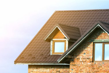 Yeni tugla ev kahverengi shingle çatı ve Plastik tavan windows parlak mavi gökyüzü arka plan üzerinde yakın çekim detayını. Gayrimenkul ve profesyonelce yapılan iş kavramı.