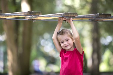 Portre sevimli tatlı gülümseyen sarışın kız yaz pembe elbise kaldırdı kollarını bulanık yeşil güneşli ışık kopya alanı bokeh arka plan yolda ipi tutan. Eğlence ve oyun kavramı.