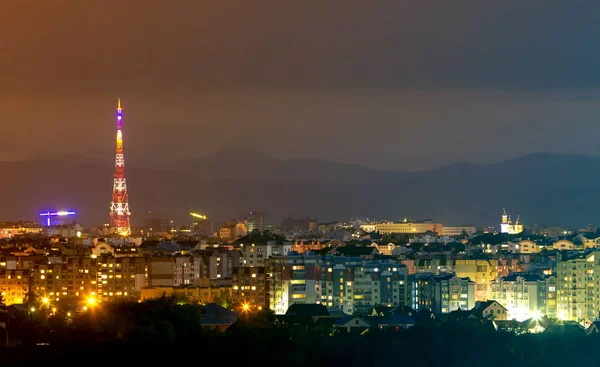 広いパノラマ 近代的な観光イヴァーノ フランキーウシク市 ウクライナの空中夜景 背の高い建物 高いテレビ塔 カルパティア山脈の背景に緑豊かな郊外の明るいライトのシーン — ストック写真