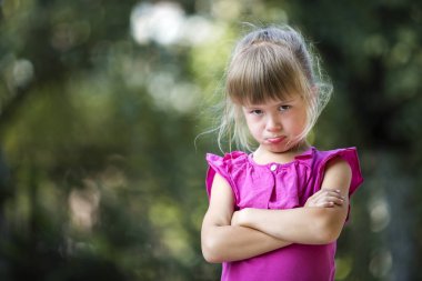 Duygu kızgın ve tatminsiz bulanık yaz yeşil ağaç kopyalama alanı bokeh arka plan üzerinde pembe kolsuz elbise kız çok komik moody mutsuz genç sarışın çocuk portresi. Çocuk öfke nöbeti kavramı.