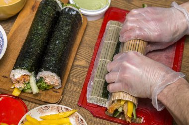 Suşi ve rulo yapma işlemi. Yakın çekim adam şef eller ev ya da mutfak masasında Restoran geleneksel Japon gıda hazırlama.