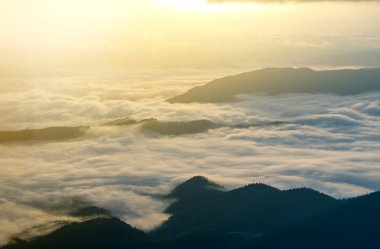 Dağ vadinin muhteşem manzarası kaplı düşük beyaz kabarık gibi kar sisli ufuk ışık turuncu parlamayı gündoğumu, parlak sabah gökyüzü altında uzanan bulutlar. Doğa kavramının güzellik.