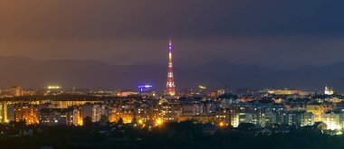 Geniş panorama, modern turistik Ivano-Frankivsk City, Ukrayna hava gece görünümü. Yüksek binalar, yüksek televizyon kulesi ve Karpat Dağları zemin üzerine yeşil banliyölerde parlak ışıkları sahne.