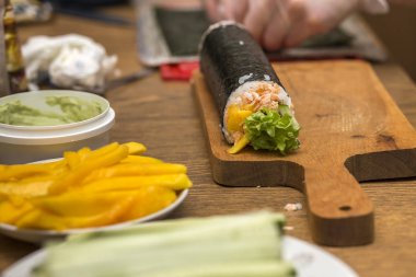 Ev yapımı suşi ve rulo. Ahşap mutfak masasında, tahtada geleneksel Japon yiyecek ve suşi rulo için malzemeler ile plakalar görüntülemek yukarıdan.