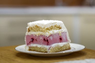 Beyaz tabak taze lezzetli lezzetli ev yapımı parça meyve bisküvi beyaz ve pembe kremalı pasta üzerinde ışık mutfak masasında ile kopya alan arka plan bulanık. Ekmek pasta ve sağlıklı gıda kavramı yapma.