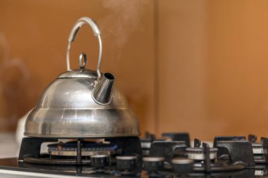 Kaynar su gaz ile parlak paslanmaz çay çaydanlık çaydanlık mutfak sarı kopya alan arka plan üzerinde soba.