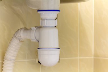 Yeni modern seramik beyaz lavabo lavabo bağlantı kanalizasyon için ayrıntı görünümünü kopya alan arka plan açık bej seramik karo üzerinde. Profesyonel tesisat ve montaj kavramı.