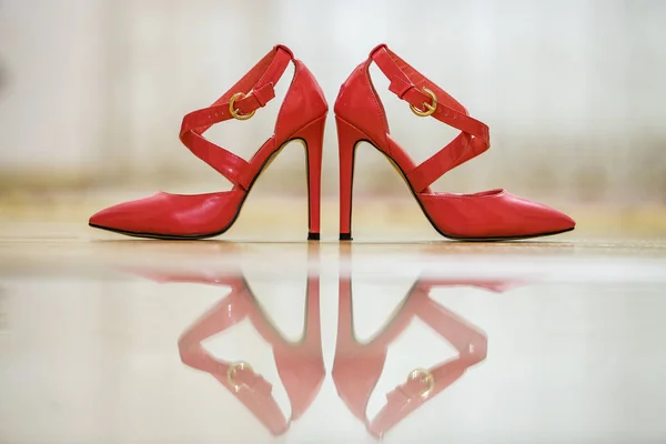 Pair of fashionable high heel leather red cut-out female shoes with golden buckles isolated on light copy space background. Style and fashion, modern footwear concept.