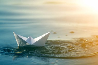 Basit küçük beyaz origami kağıt tekne mavi temiz nehir veya deniz su parlak yaz göğün altında yüzen Close-up. Doğa, özgürlük, düşler ve fantasies kavramının güzellik.