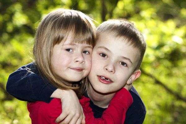两个可爱的金发碧眼的搞笑快乐微笑的孩子兄弟姐妹 小男孩兄弟拥抱姐妹女孩户外在明亮的阳光明媚的绿色波克的背景 家庭关系 友谊和爱情观念 — 图库照片