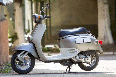 Yeni beyaz parlak motosiklet scooter iki aynalar ve el freni ile bulanık güneşli kırsal arka plan üzerinde park etmiş. Rahat şehir ve off-road nakliye, yakıt ekonomisi, seyahat ve hız kavramı.