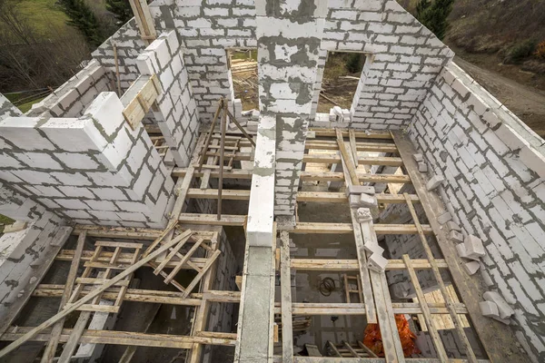 View from above of future multi stored cottage energy saving walls of large white hollow foam insulation blocks and temporary wooden scaffolding frame. Construction masonry, modern technology concept.