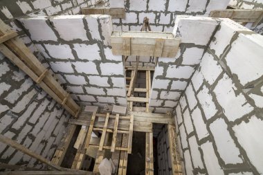 Yukarıdan gelecekteki multi depolanan yazlık enerji tasarrufu büyük beyaz içi boş köpük yalıtım blokları ve geçici ahşap iskele çerçeve görüntüleyin. İnşaat duvar, modern teknoloji kavramı.