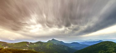 Dağ yamacı yeşil çim ve Karpat Dağları ile dramatik bulutlar gökyüzü gün ışığında sisli Hills güzel manzarasına. Doğa kavramının güzellik.