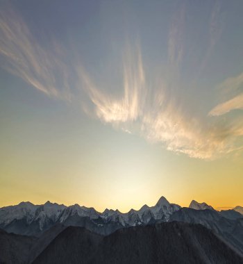 Dağ şafakta panorama manzara kış. Sarp dağ zirveleri karla kaplı ve odunsu tepeler üzerinde parlak güneşin yükselterek Ladin ormanla gündoğumu kopya alan arka plan mavi gökyüzüne temizleyin.