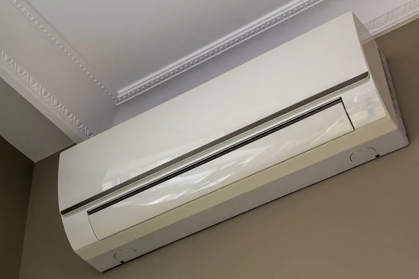 Cool air conditioner installed in room interior on white ceiling and light walls copy space background. Climate control, comfortable home concept.