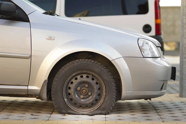 Flat tire of car on pavement. Side view outdoors of vehicle close up. Transportation problem, accident and insurance concept.