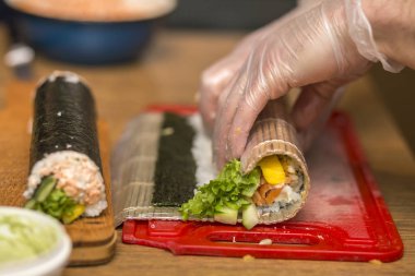 Suşi ve rulo yapma işlemi. Yakın çekim adam şef eller ev ya da mutfak masasında Restoran geleneksel Japon gıda hazırlama.