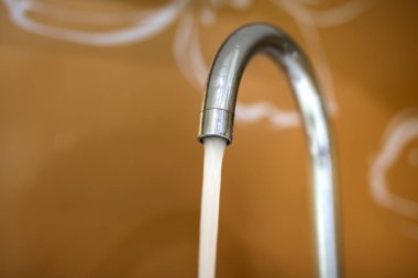 Musluk suyu, banyo veya mutfak, mikser soğuk sıcak su parlak sarı kopya alan arka plan üzerinde izole su akışı çalışan ile krom paslanmaz metal musluk. Modern mutfak iç.