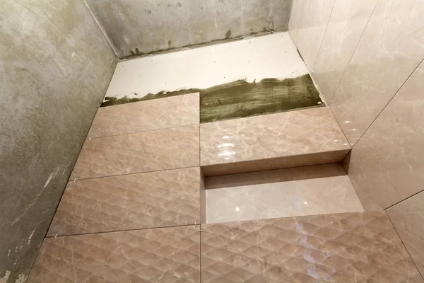 Bitmemiş iş, hafif bej seramik karo banyo veya tuvalet duvarları üzerinde yüklü. Fayans yükleme, ev geliştirme, tadilat ve inşaat, konforlu modern ev concept.