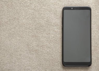 Hafif kumaş kopya alan arka plan üzerinde izole yeni siyah modern cep telefonu. Modern teknoloji, iletişim ve gadget tasarım konsepti.