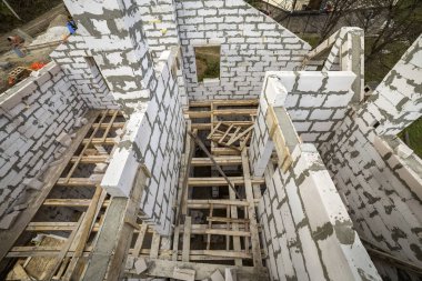 Yukarıdan gelecekteki multi depolanan yazlık enerji tasarrufu büyük beyaz içi boş köpük yalıtım blokları ve geçici ahşap iskele çerçeve görüntüleyin. İnşaat duvar, modern teknoloji kavramı.