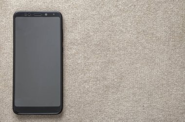 Hafif kumaş kopya alan arka plan üzerinde izole yeni siyah modern cep telefonu. Modern teknoloji, iletişim ve gadget tasarım konsepti.