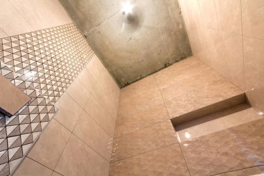 Banyo veya tuvalet lavabo ve banyo için yer ile hafif bej geometrik Mozaik Seramik duvarlar, yüklü tamamlanmamış inşası. Düşük açılı, alttan görünüm.