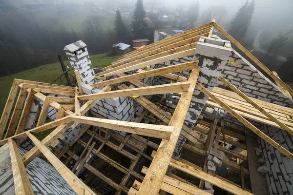 Top view of roof frame from wooden lumber beams and planks on walls made of hollow foam insulation blocks. Building, roofing, construction and renovation concept.