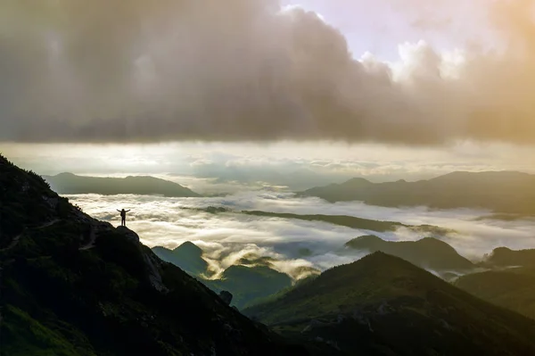 宽广的山全景 小剪影的游客与背包在洛基山坡上举起手在山谷覆盖着白色的肿胀云 自然美 旅游观与旅游理念 — 图库照片