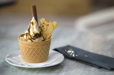 Dondurma Tatlı gofret fincan çikolatalı kurabiye ve yaratıcı dekorasyon Tepesi bulanık renkli iç arka plan üzerinde beyaz plaka.