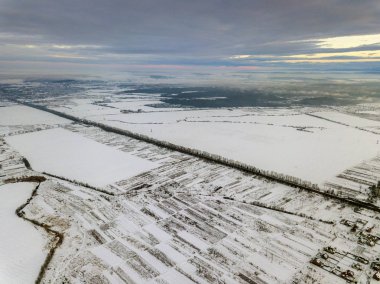 Dramatik bulutlu gökyüzü arka plan üzerinde kış sabahı üstten görünüm boş karlı alanları. Hava dron fotoğraf kavramı.