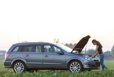 Genç bir kadın ve bir araba ile haşhaş kukuleta. Ulaşım, araç sorunları ve arıza kavramı.